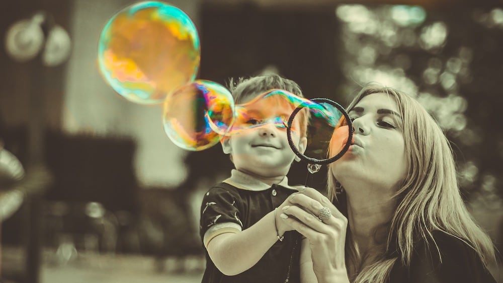 mom blowing bubbles with child