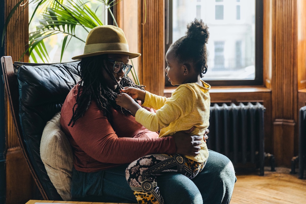 Daughter playing with mothers hair in living room