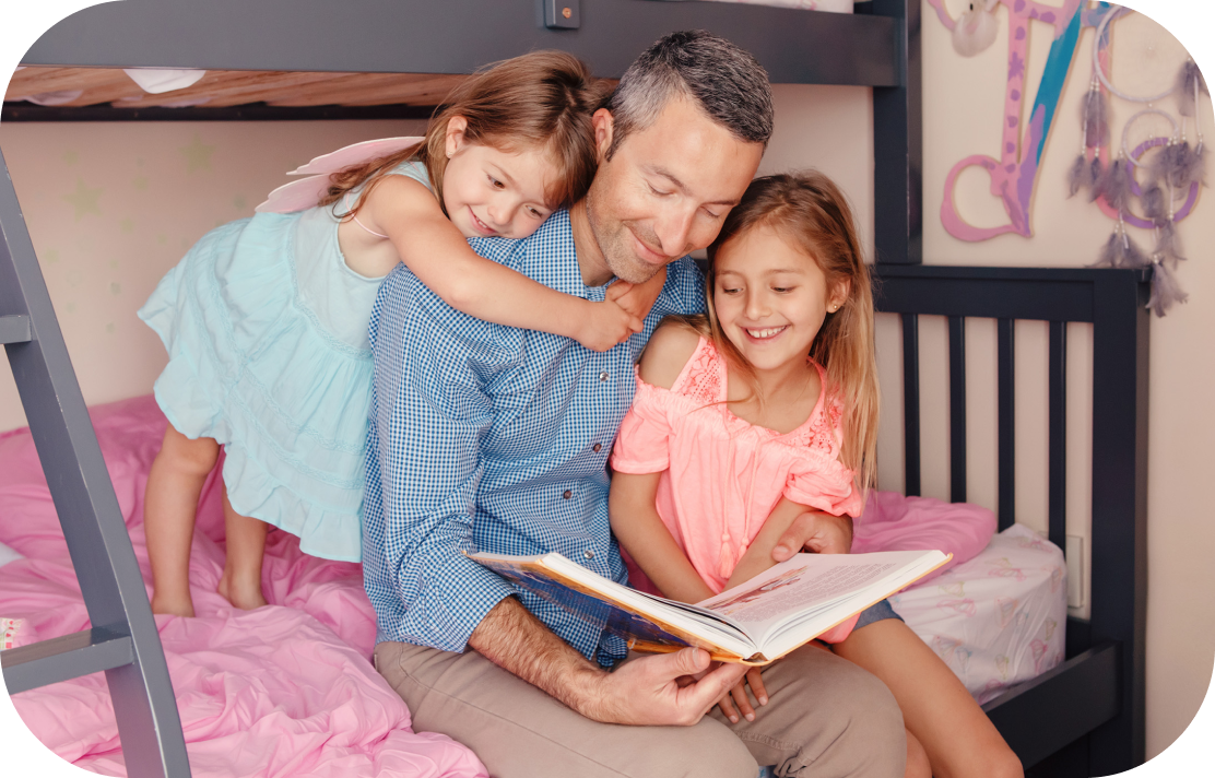 two daughters reading a book with their father