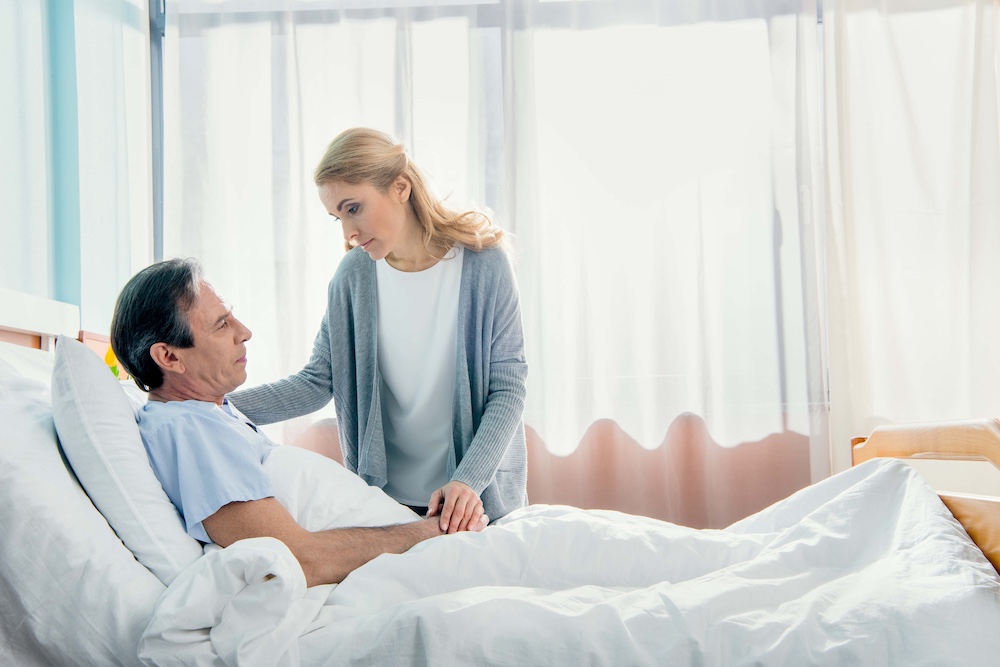 wife visiting pensive elderly husband in hospital